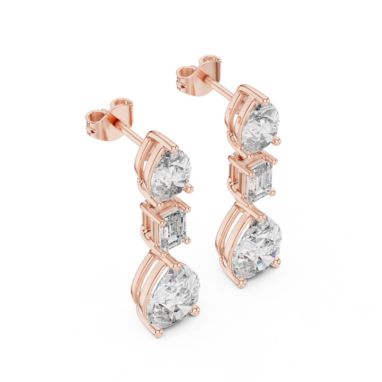 Side profile of rose gold pear and emerald cut diamond drop earrings.