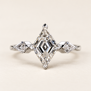 Lozenge step cut Lab Grown Diamond three stone engagement ring in white gold with matching lozenge side diamonds and double-claw prongs.