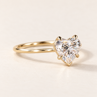 Heart cut lab grown diamond solitaire engagement ring in yellow gold with four claw prongs, a V-shaped point guard and a plain band