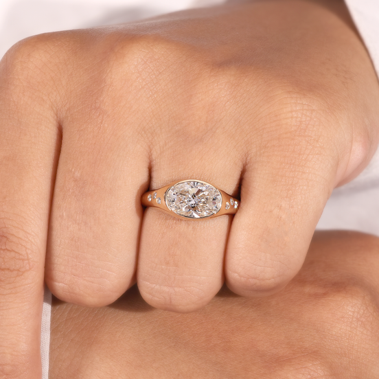 Yellow gold oval lab grown diamond men's signet ring with partial bezel setting and flush-set shoulder diamonds.