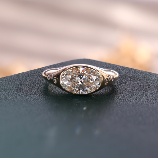 Yellow gold oval lab grown diamond men's signet ring with partial bezel setting and flush-set shoulder diamonds.