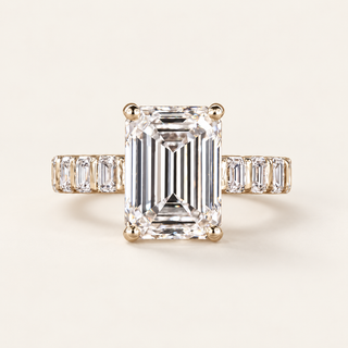 Emerald cut lab grown diamond engagement ring with a 5.00 ct center, four-prong setting and emerald cut diamond shoulders in polished yellow gold.