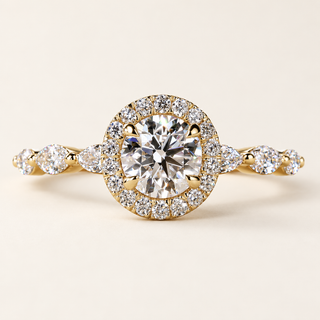 Round lab grown diamond halo engagement ring in yellow gold with four center prongs, pavé halo and marquise-and-round diamond shoulders