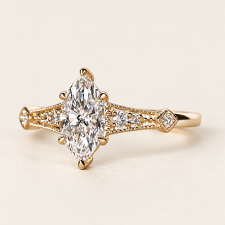 Marquise cut lab grown diamond cathedral engagement ring with a prong-set center, pavé diamond shoulders, Art Deco milgrain and geometric yellow gold detailing.