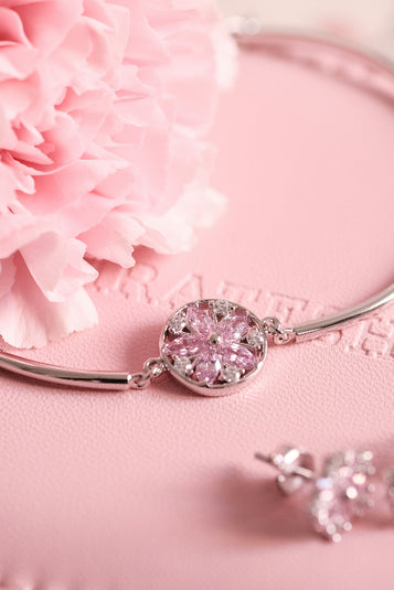 Silver jewelry set with pink gemstones on a pink surface