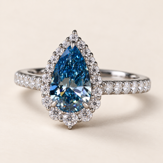 Blue pear cut lab grown diamond halo engagement ring in white gold with three center prongs, round diamond surround and pavé shoulders