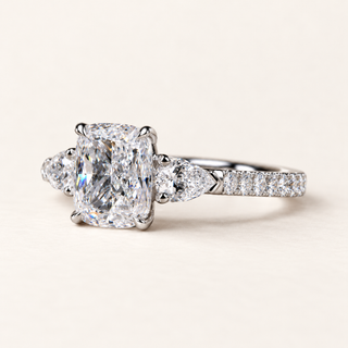 Elongated cushion cut lab grown diamond three stone engagement ring in white gold with pear side diamonds and pavé shoulders