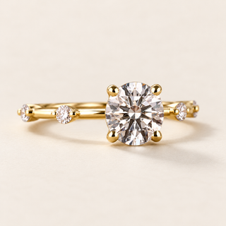 Round lab grown diamond four-prong engagement ring in yellow gold with spaced round diamond accents and slim polished band