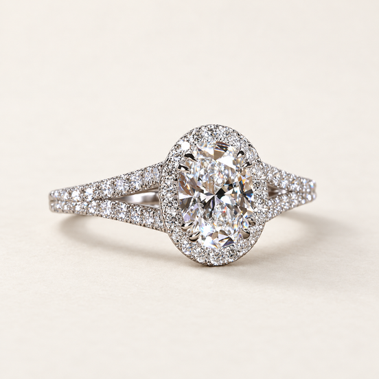 Oval cut lab grown diamond halo engagement ring in white gold with round diamond halo, pavé split shank and open triangular shoulders.