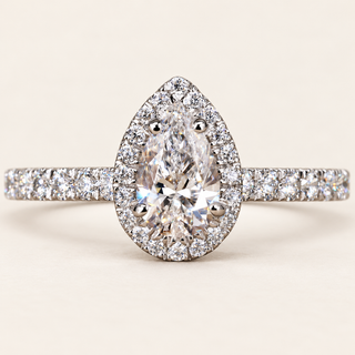 Pear cut lab grown diamond halo engagement ring in white gold with four rounded center prongs, pear-shaped halo and pavé shoulders