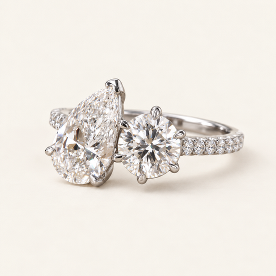 Pear cut lab grown diamond two-stone engagement ring with 2.00 ct pear, 1.25 ct round diamond, raised open baskets and pavé shoulders in white gold.