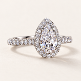 Pear cut lab grown diamond halo engagement ring in white gold with four rounded center prongs, pear-shaped halo and pavé shoulders