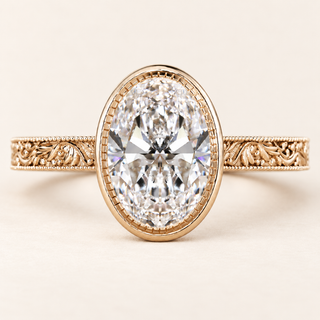 Oval cut lab grown diamond engagement ring with a full milgrain-detailed bezel, ornate filigree shoulders and polished yellow gold band.