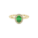 Close-up, oval cut emerald green gemstone, yellow gold french pavé halo ring.