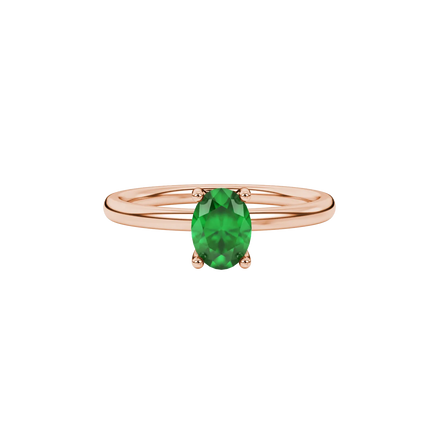 Close-up, oval cut emerald green gemstone ring, rose gold surprise diamond setting.