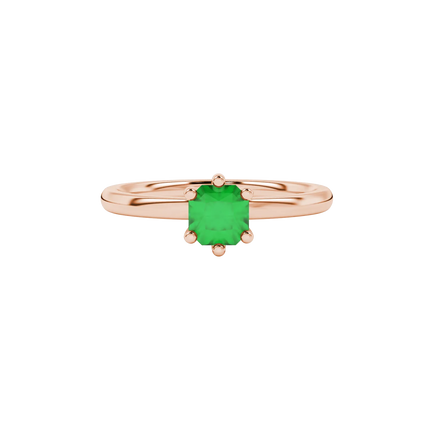 close-up shot of a radiant emerald green gemstone ring with a classic rose gold six-prong setting.