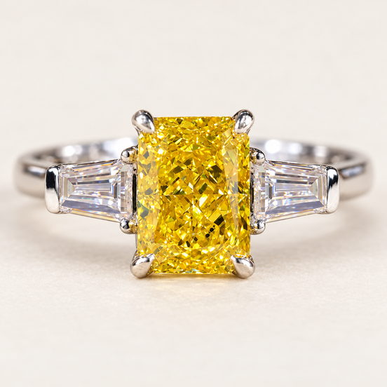 Vivid yellow radiant cut lab grown diamond three stone engagement ring in white gold with four-prong center and tapered baguette accents