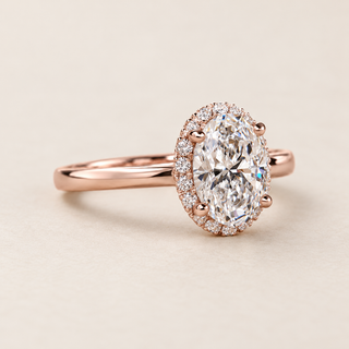 Oval cut lab grown diamond halo engagement ring with 1.50 ct center, round diamond halo and plain polished rose gold band.