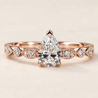 Pear cut lab grown diamond vintage engagement ring in rose gold with protective V-prong, leaf-inspired openwork shoulders and round diamond accents.