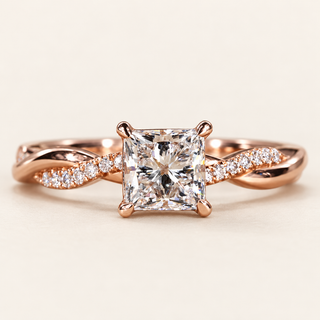 Princess cut lab grown diamond split shank engagement ring in rose gold with four corner prongs and pavé shoulders crossing polished metal strands.
