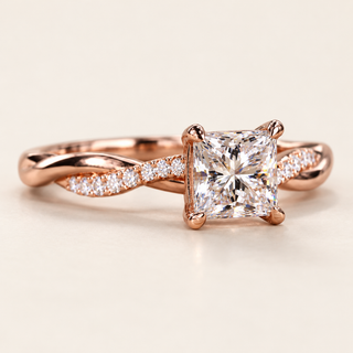 Princess cut lab grown diamond split shank engagement ring in rose gold with four corner prongs and pavé shoulders crossing polished metal strands.