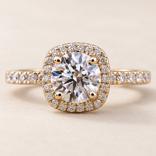 Round lab grown diamond engagement ring in yellow gold with cushion-shaped pavé halo, four-prong center and diamond shoulders
