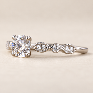 Round lab grown diamond vintage milgrain engagement ring in white gold with four-prong center, beaded leaf shoulders and diamond accents