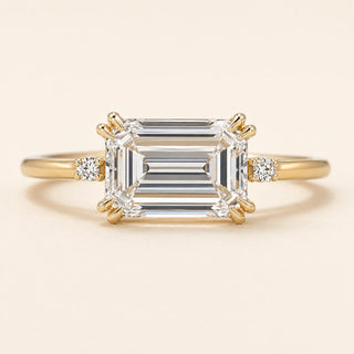 Emerald cut Lab Grown Diamond east-west engagement ring in yellow gold with a double-claw four-prong cathedral setting and hidden side diamonds.