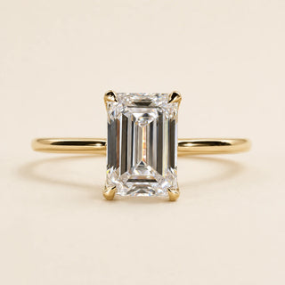 Emerald cut Lab Grown Diamond solitaire engagement ring in yellow gold with four double-claw prongs and an open cathedral basket.