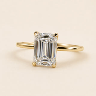 Emerald cut Lab Grown Diamond solitaire engagement ring in yellow gold with four double-claw prongs and an open cathedral basket.
