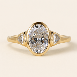 Oval Lab Grown Diamond Bezel Three-Stone Engagement Ring with Trillion Side Diamonds in Yellow Gold