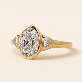 Oval Lab Grown Diamond Bezel Three-Stone Engagement Ring with Trillion Side Diamonds in Yellow Gold