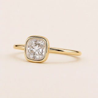 Cushion cut Lab Grown Diamond bezel engagement ring in yellow gold with a full bezel setting and open basket gallery.