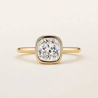 Cushion cut Lab Grown Diamond bezel engagement ring in yellow gold with a full bezel setting and open basket gallery.