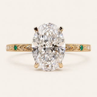 Oval Lab Grown Diamond vintage engagement ring in yellow gold with a hidden halo, engraved shank and emerald side accents.