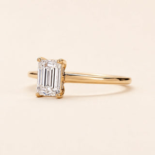 Emerald cut Lab Grown Diamond solitaire engagement ring in yellow gold with a four-prong cathedral open basket setting.