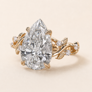 Pear cut lab grown diamond cluster engagement ring in yellow gold with sculptural leaf-and-vine shoulders