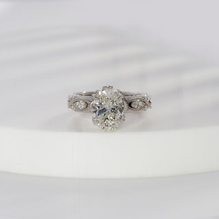 Oval cut lab grown diamond vintage engagement ring in white gold with marquise and round diamond accents and milgrain scrollwork