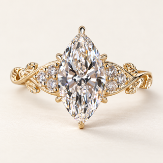 Marquise cut lab grown diamond engagement ring with a 2 ct center, protective tip prongs, six round diamond accents and leaf-and-vine yellow gold shoulders.