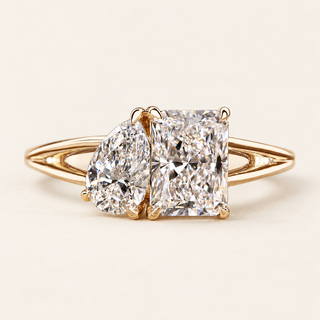 Radiant and pear cut lab grown diamond Toi et Moi engagement ring with asymmetrical prong baskets and polished yellow gold split shank.