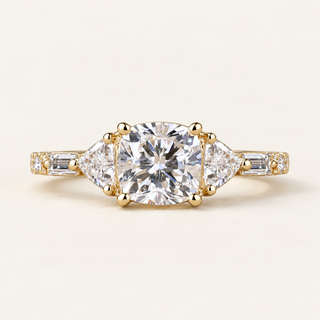 Cushion cut lab grown diamond three-stone engagement ring with 1.00 ct center, trillion side diamonds, baguette accents and polished yellow gold band.