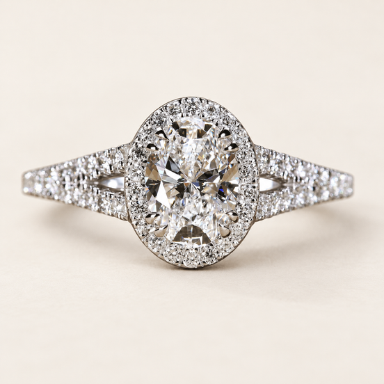 Oval cut lab grown diamond halo engagement ring in white gold with round diamond halo, pavé split shank and open triangular shoulders.