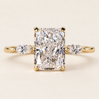 Radiant cut lab grown diamond three-stone engagement ring in yellow gold with two marquise side diamonds and four-prong center setting.