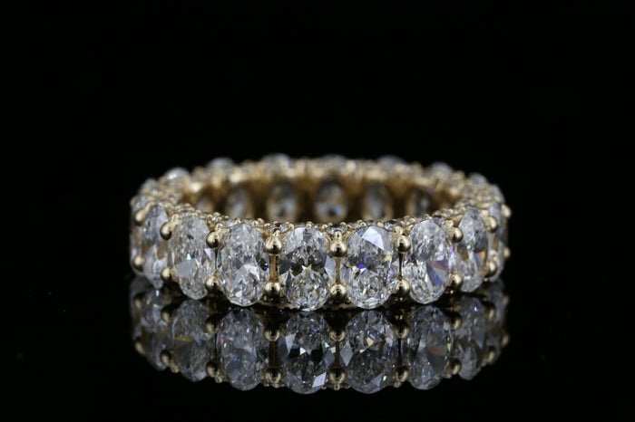 Yellow gold eternity ring with 5.280ct oval lab grown diamonds photographed on black