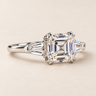 Asscher cut lab grown diamond three-stone engagement ring in white gold with two tapered baguette side diamonds, paired corner claws and polished shank.