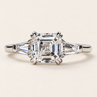 Asscher cut lab grown diamond three-stone engagement ring in white gold with two tapered baguette side diamonds, paired corner claws and polished shank.
