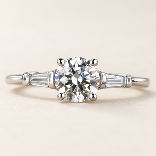 Round cut lab grown diamond three-stone engagement ring in white gold with tapered baguette side diamonds and polished band
