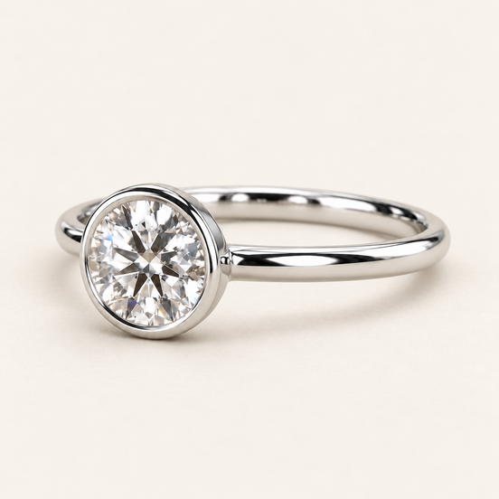 Round lab grown diamond bezel engagement ring in white gold with a continuous polished rim and plain band