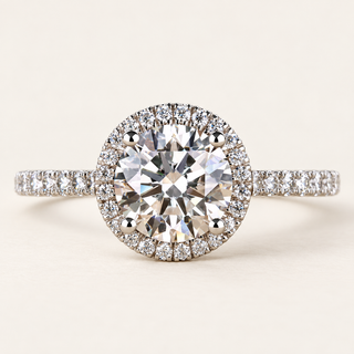 Round lab grown diamond halo engagement ring in white gold with four-prong center, pavé halo and diamond-set shoulders