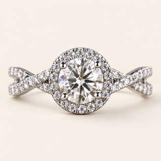 Round lab grown diamond crossover engagement ring in white gold with four-prong center, pavé halo and twisting diamond shoulders